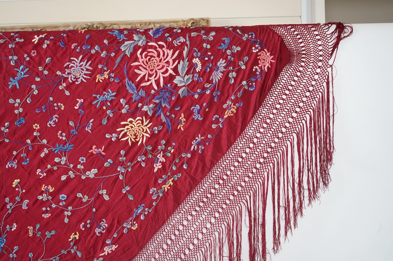 A late 19th early 20th century Chinese silk polychrome embroidered shawl on a maroon silk background. Fringed. 180cm x 60cm. Condition - no fading to colours, silk good